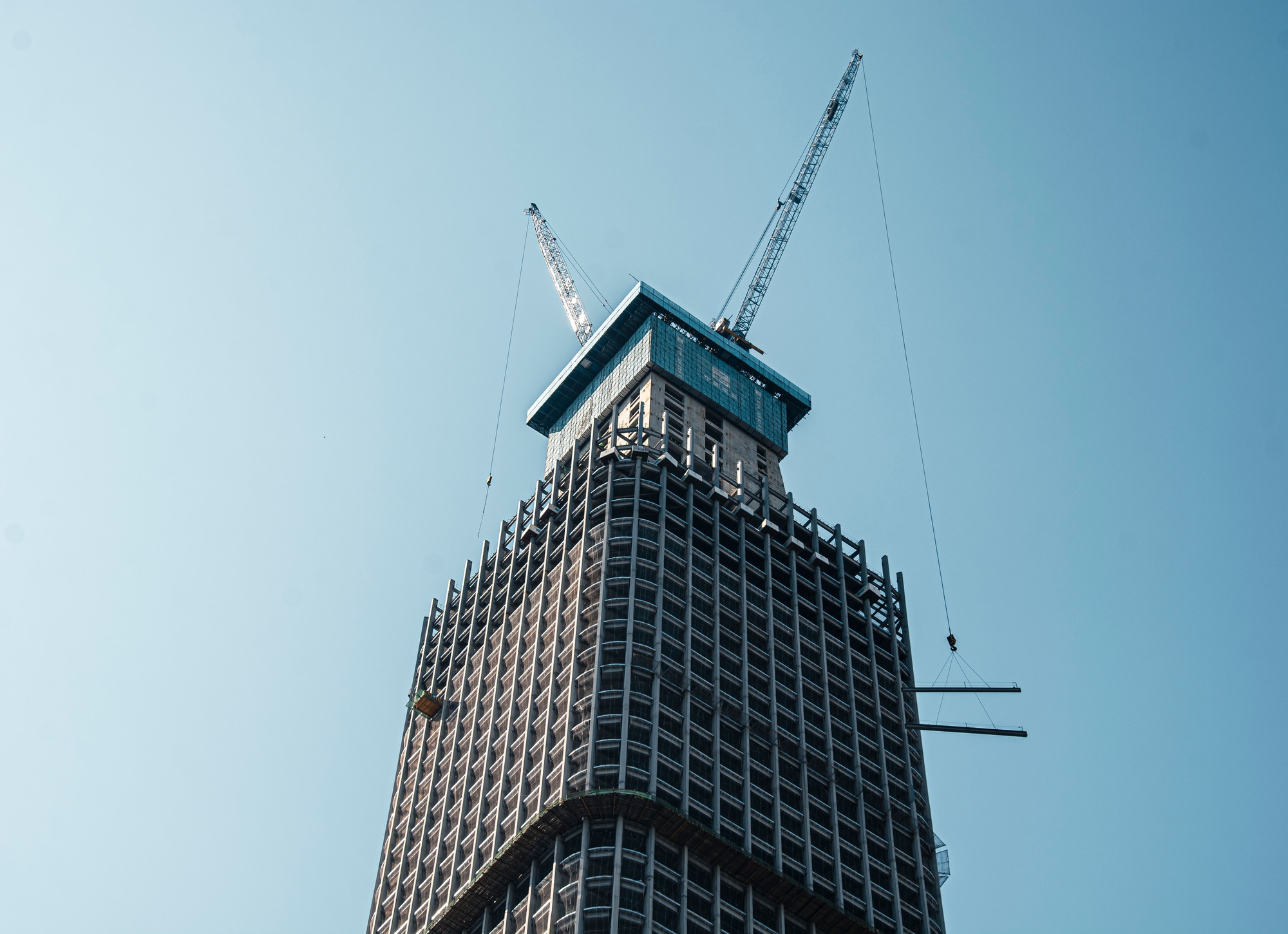 High-rise building under construction with cranes.